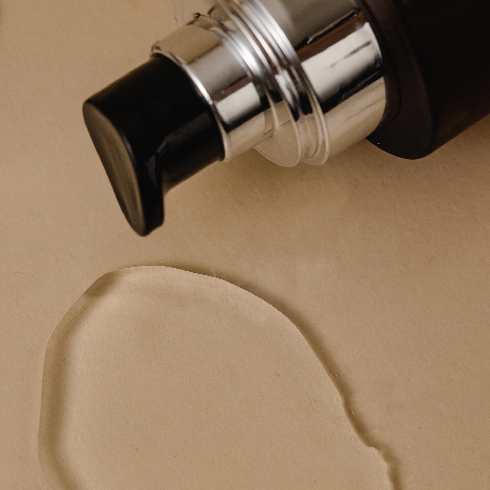 Sandalwood hydrating body oil - urban veda bottle showing a pour on a light coloured background